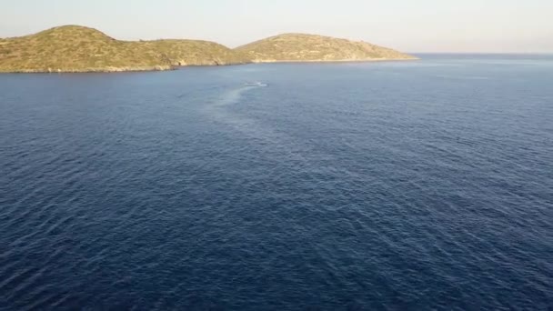 Vista aérea de un barco de motos acuáticas en un mar de color azul profundo. Isla Spinalonga, Creta, Grecia — Vídeos de Stock