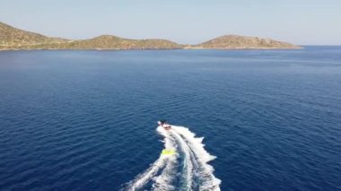 Motorlu bir teknenin tüpü çektiği hava görüntüsü. Elounda, Girit, Yunanistan