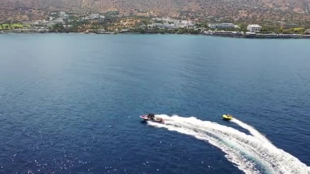 Luftaufnahme eines Motorbootes, das eine Röhre zieht. Elounda, Kreta, Griechenland — Stockvideo