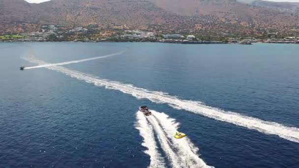 Aerial view of a motor boat towing a tube. Elounda, Crete, Greece — Stock Video