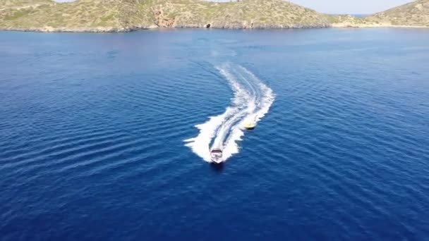 Vue aérienne d'un bateau à moteur remorquant un tube. Elounda, Crète, Grèce — Video