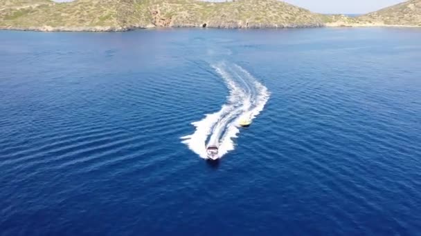 Vista aérea de um barco a motor rebocando um tubo. Elounda, Creta, Grécia — Vídeo de Stock