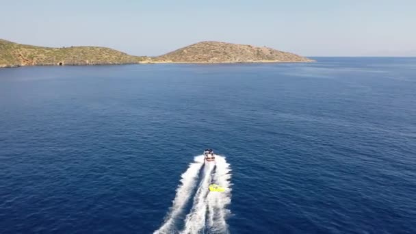 Вид с воздуха на моторную лодку, буксирующую трубку. Элоунда, Крит, Греция — стоковое видео