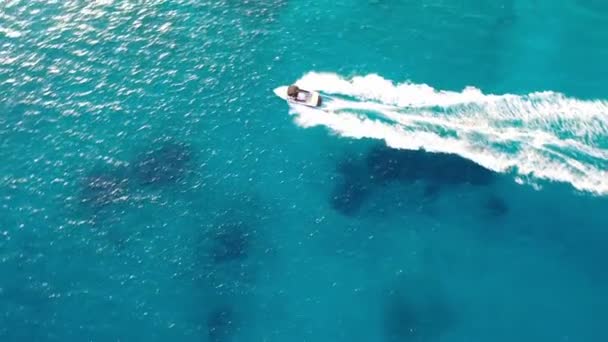 Flygfoto av en motorbåt som bogserar en vattenskidåkare. Elounda, Kreta, Grekland — Stockvideo