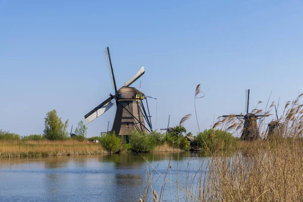 Vista aérea de un antiguo molino de viento tradicional holandés en el campo rural en los Países Bajos con un dique, canales, puente y campos . — Foto de Stock