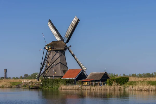 Vista aérea de un antiguo molino de viento tradicional holandés en el campo rural en los Países Bajos con un dique, canales, puente y campos . —  Fotos de Stock