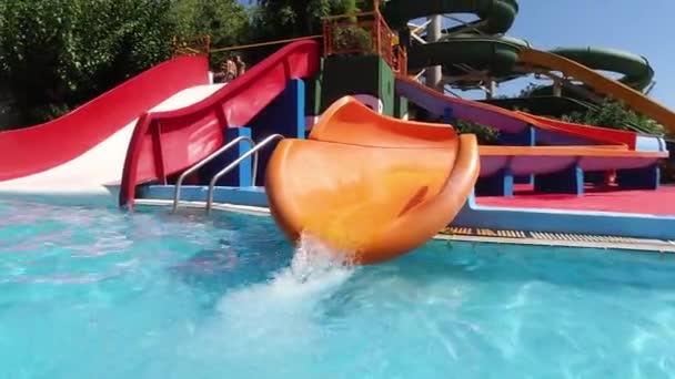 Niña feliz divirtiéndose con tobogán de agua en una piscina disfrutando de una excursión de un día a un parque de atracciones acuático durante las vacaciones familiares de verano — Vídeo de stock