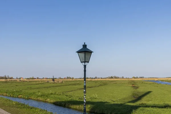 Vista aérea de un antiguo molino de viento tradicional holandés en el campo rural en los Países Bajos con un dique, canales, puente y campos . — Foto de Stock