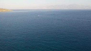 Koyu mavi bir denizde bir jet ski teknesinin hava görüntüsü. Spinalonga Adası, Girit, Yunanistan