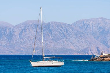 Beyaz yay ve arka planda dağlarla kıyı manzaralı yaz denizi Yunanistan