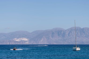 Beyaz yay ve arka planda dağlarla kıyı manzaralı yaz denizi Yunanistan