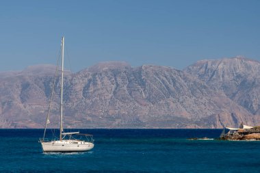 Beyaz yay ve arka planda dağlarla kıyı manzaralı yaz denizi Yunanistan