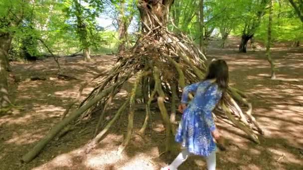 Mała dziewczynka bawiąca się w wickup, chata zrobiona z brunchów btree w Epping Forest, Loughton, Londyn — Wideo stockowe