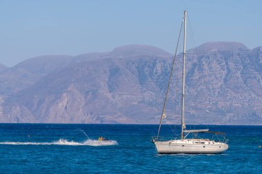 Beyaz yay ve arka planda dağlarla kıyı manzaralı yaz denizi Yunanistan