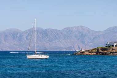 Beyaz yay ve arka planda dağlarla kıyı manzaralı yaz denizi Yunanistan