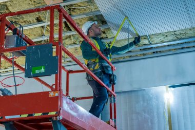 portrait of young drylining contractor installing ceiling on construction site clipart