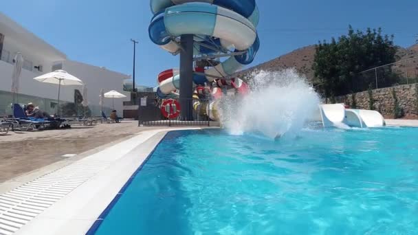 Homem se divertindo no parque aquático. Ele está deslizando para baixo da atração em câmera lenta. Thera são muitos respingos aroun ele, Creta, Greece — Vídeo de Stock