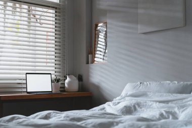 Boş ekranı kopyalayan dizüstü bilgisayar ve beyaz sayfalı yatak