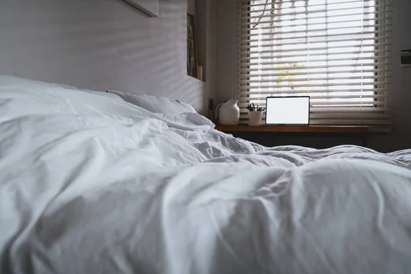 Ноутбук з копіювальним простором порожній екран і ліжко з білими листами — стокове фото
