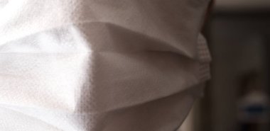 Tıbbi ya da cerrahi maske takan genç bir adamın yüzüyle yakın çekim.