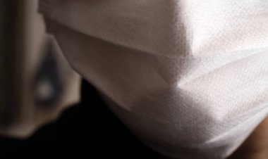 Tıbbi ya da cerrahi maske takan genç bir adamın yüzüyle yakın çekim.