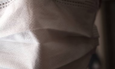 Tıbbi ya da cerrahi maske takan genç bir adamın yüzüyle yakın çekim.