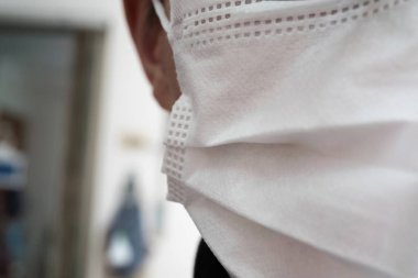 Tıbbi ya da cerrahi maske takan genç bir adamın yüzüyle yakın çekim.