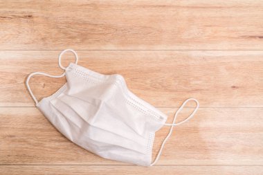 Ahşap masa arkasında koruyucu tıbbi maske.