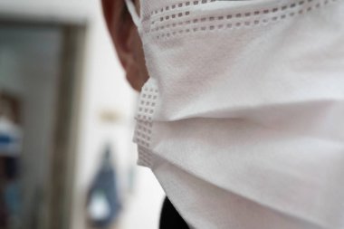 Tıbbi ya da cerrahi maske takan genç bir adamın yüzüyle yakın çekim.