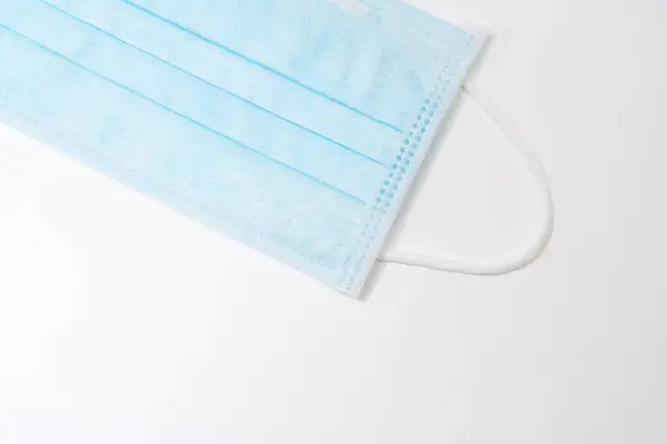 Surgical mask with rubber ear straps. Typical 3-ply surgical mask to cover the mouth and nose. Procedure mask from bacteria. Protection concept.