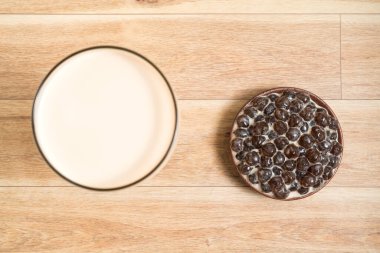 Bir bardak inci sütlü çay (köpüklü çay olarak da bilinir) ve ahşap zemin üzerinde bir tabak tapyoka topu. İnci sütlü çay Tayvan 'daki en temsili içecektir. Tayvan yemeği. Kopyalama alanı ile.