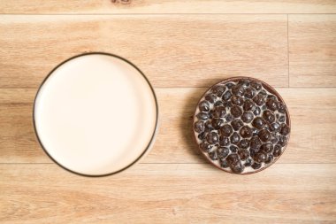 Bir bardak inci sütlü çay (köpüklü çay olarak da bilinir) ve ahşap zemin üzerinde bir tabak tapyoka topu. İnci sütlü çay Tayvan 'daki en temsili içecektir. Tayvan yemeği. Kopyalama alanı ile.