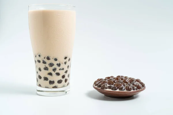 A glass cup of pearl milk tea (also called bubble tea) and a plate of tapioca ball on white background. Pearl milk tea is the most representative drink in Taiwan. Taiwan food . With copy space.