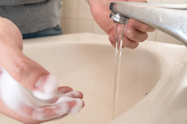 Hygiene concept. Washing hands with soap under the faucet with water