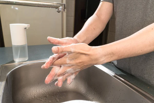 Hygiene concept. Washing hands with soap under the faucet with water
