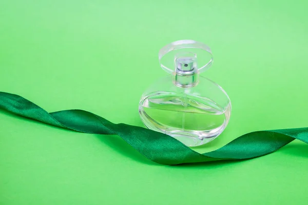 กลิ่นหอมบนพื้นหลังสีเขียว น้ําหอมกับริบบิ้นของขวัญ กลิ่นหอมวินเทจกับสเปรย์ . — ภาพถ่ายสต็อก