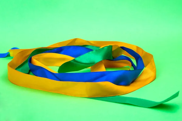 Yeşil arka planda renkli kurdeleler. Saten kurdeleler yakın plan..