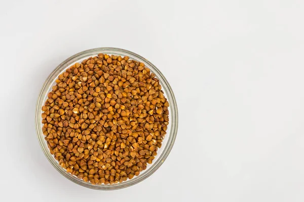 Karabuğday beyaz arka planda bir tabakta inliyor. Küçük bir tabakta karabuğday lapası. Diyet kahvaltı. Sağlıklı yemek..