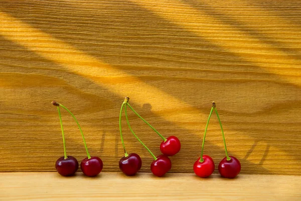 Cerezas rojas maduras sobre un fondo de madera. Frutos sobre un fondo de madera marrón . — Foto de Stock