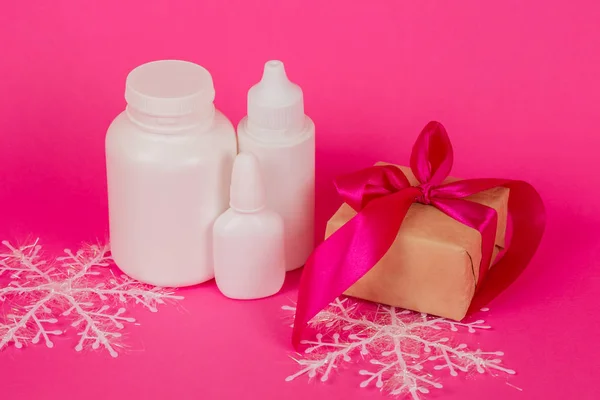 Косметика и подарок с розовой лентой. Белые бутылки на розовом фоне. Косметический набор на розовом фоне . — стоковое фото