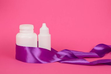 Pembe arka planda beyaz şişeler. Hediye kadın takımı. Saç bakım ürünleri. Kurdeleli beyaz şişe..