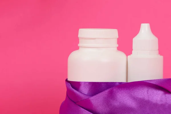 Белые бутылки на розовом фоне. Подарочный женский набор. Продукт по уходу за волосами. Белая бутылка с лентой . — стоковое фото