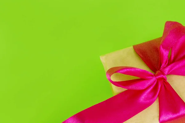 Caixa de presente embrulhada em papel artesanal. presente com uma fita rosa em um fundo verde. Dia dos Namorados. 8 de Março — Fotografia de Stock