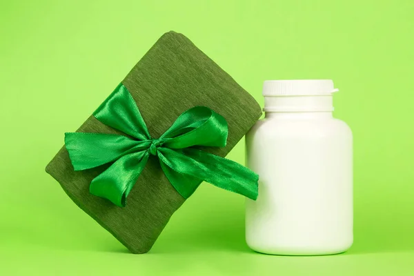 Подарок в зеленой упаковке и белой бутылке. Подарочная коробка на зеленом фоне. Зеленый подарок для женщины. Подарок на 8 марта . — стоковое фото