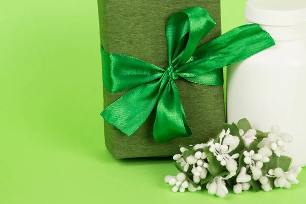 Подарок в зеленой упаковке и белой бутылке. Подарочная коробка на зеленом фоне. Зеленый подарок для женщины. Подарок на 8 марта . — стоковое фото