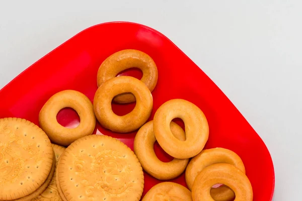 Tabakta taze simit var. Kırmızı tabakta ev yapımı kurabiyeler. Beyaz arka planda ince kurabiyeler. Lezzetli diyet kraker