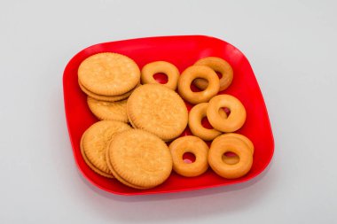 Tabakta taze simit var. Kırmızı tabakta ev yapımı kurabiyeler. Beyaz arka planda ince kurabiyeler. Lezzetli diyet kraker