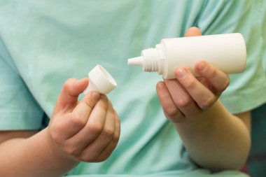 Ellerinde antiseptik olan beyaz bir şişe. Mavi arka planda antiseptik var. Coronavirus profilaksi. El dezenfektanı. Ellerini koronirüs virüsünden korumak için jel.