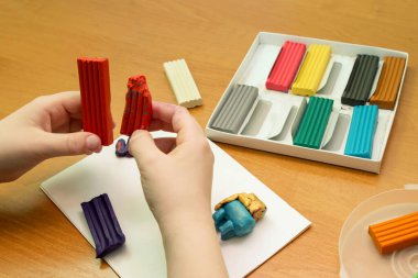 Bir çocuk plastikle oynar. Masanın üzerinde çok renkli plastiğin var. Ellerinde bir çocuğun plastiği var. Anaokulundaki çocuklar için eğitici oyunlar