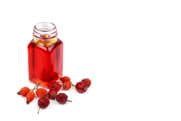 Bottle of rose hip oil and dry rose hips — Stock Photo, Image